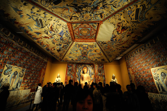 Visitors visit a replica parts of the Mogao Cave during the Dunhuang Art Exhibition in Beijing on February 20, 2008. The exhibition displays collections mostly from the Dunhuang Grottoes which were constructed between the 4th and the 14th century, including recovered antres, original painted sculptures and their replicas from Library Cave of Dunhuang. Dunhuang, located in Jiuquan of Northwest China's Gansu province along the historic Silk Road, is in danger of being swallowed by sands of the adjacent Kumtag desert, which are creeping closer at a rate of up to four metres (13 feet) a year. AFP PHOTO/TEH ENG KOON (Photo credit should read TEH ENG KOON/AFP/Getty Images)