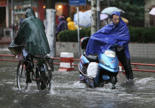 Shanghai residents struggle through flooded roads as a typhoon bears down on the city, 18 September 2007. China relocated hundreds of thousands of people as its most populous city Shanghai braced for Typhoon Wipha. The typhoon, packing winds of 180 kilometres (112 miles) an hour, was gaining strength and expected to make landfall in east China around midnight, after gale-force winds and driving rains first swipe northern Taiwan. AFP PHOTO/Mark RALSTON (Photo credit should read MARK RALSTON/AFP/Getty Images)